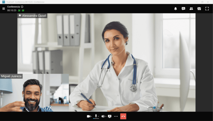 Médico y paciente en una consulta virtual, con el médico escribiendo notas y el paciente sonriendo.